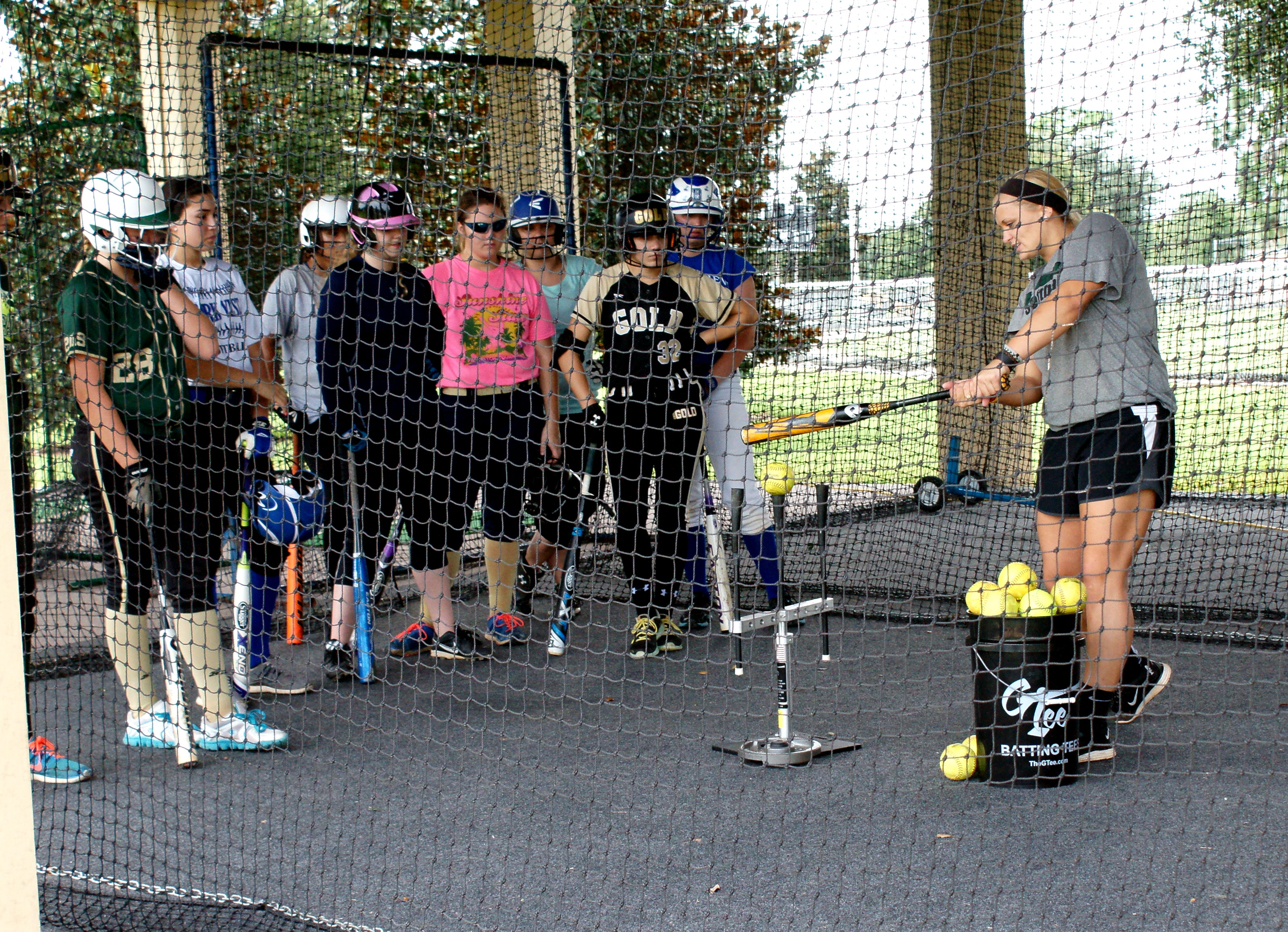 Former CF player Amy Szymanowski (L) shows softball players the correct way to hit