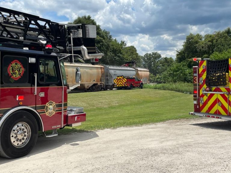 Firefighters rescue worker with a hand trapped in a conveyor belt atop a train car